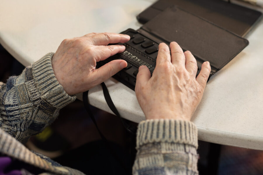 A mans hands using a braile translation device